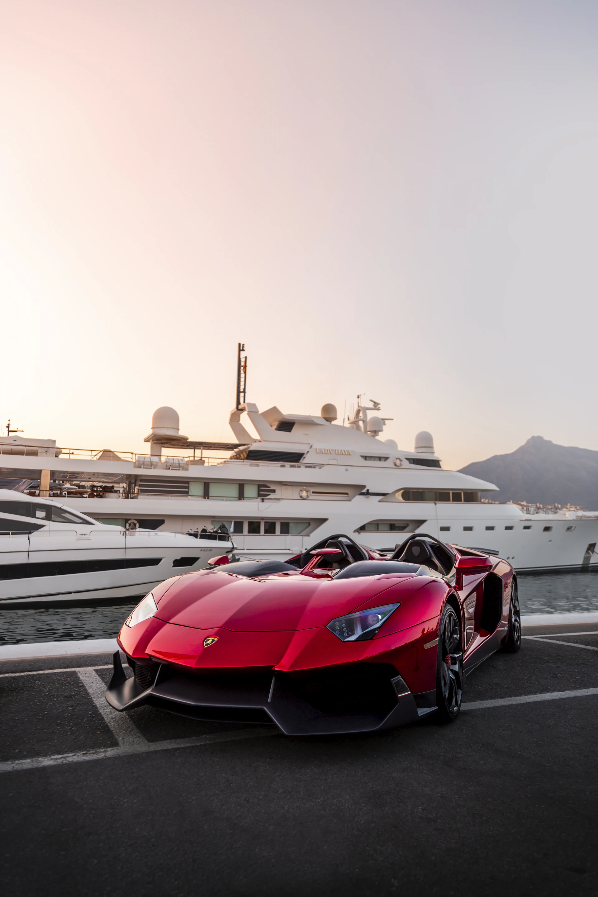 A red sports car parked in front of a yacht