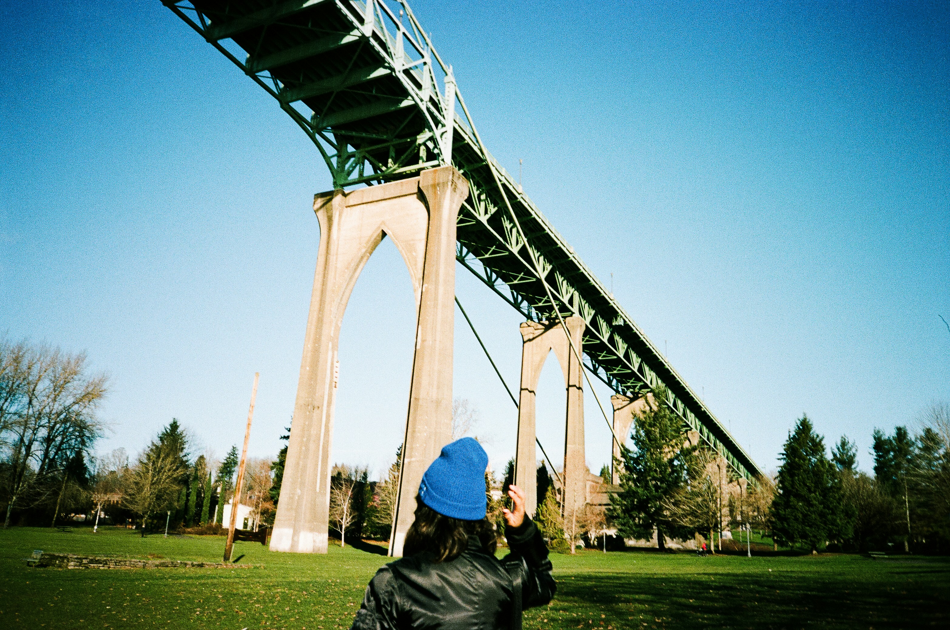 A person flying a kite under a bridge