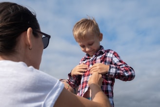 A woman is helping a young boy button his shirt