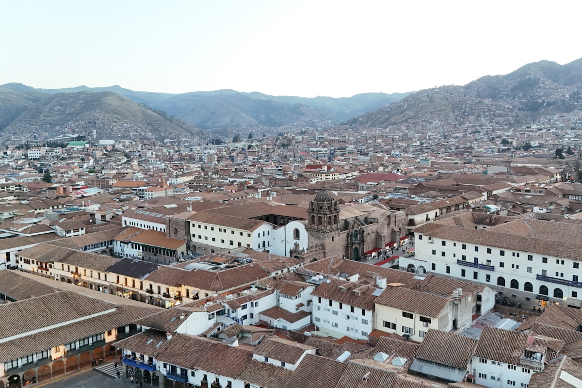 Centro Histórico Cusco — aerial view of the terracotta rooftops spreading across the Andean valley with mountains behind