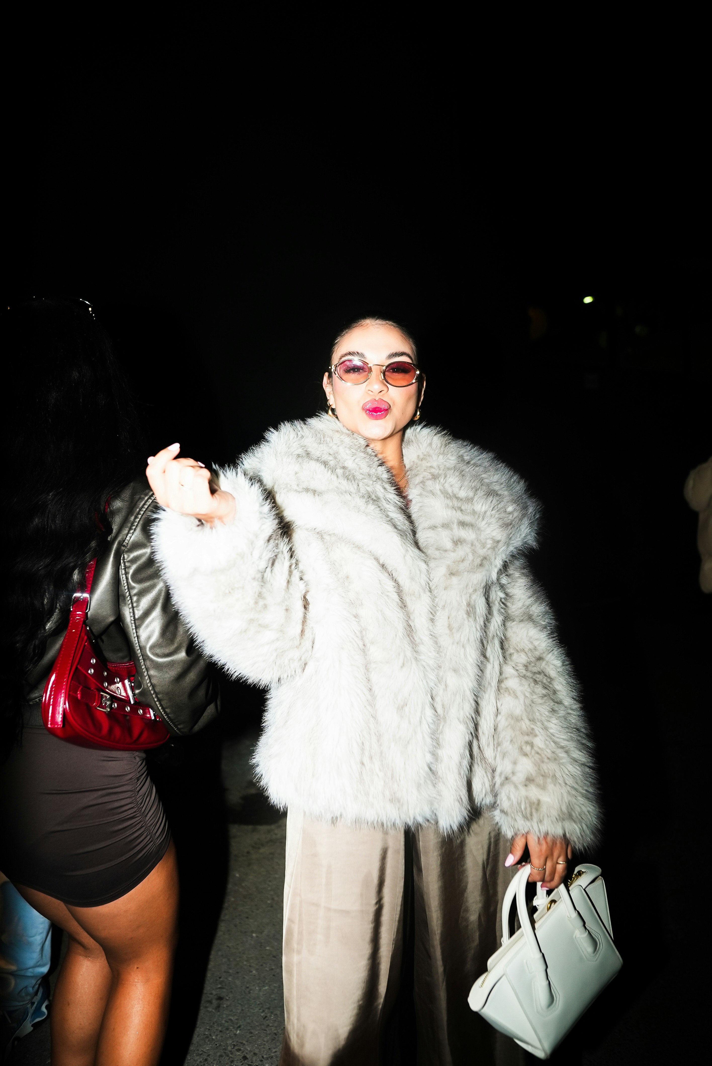 Une femme vêtue d’un manteau de fourrure et tenant un sac à main