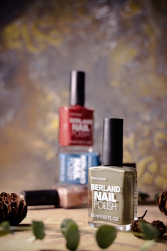 A bottle of nail polish next to some pine cones