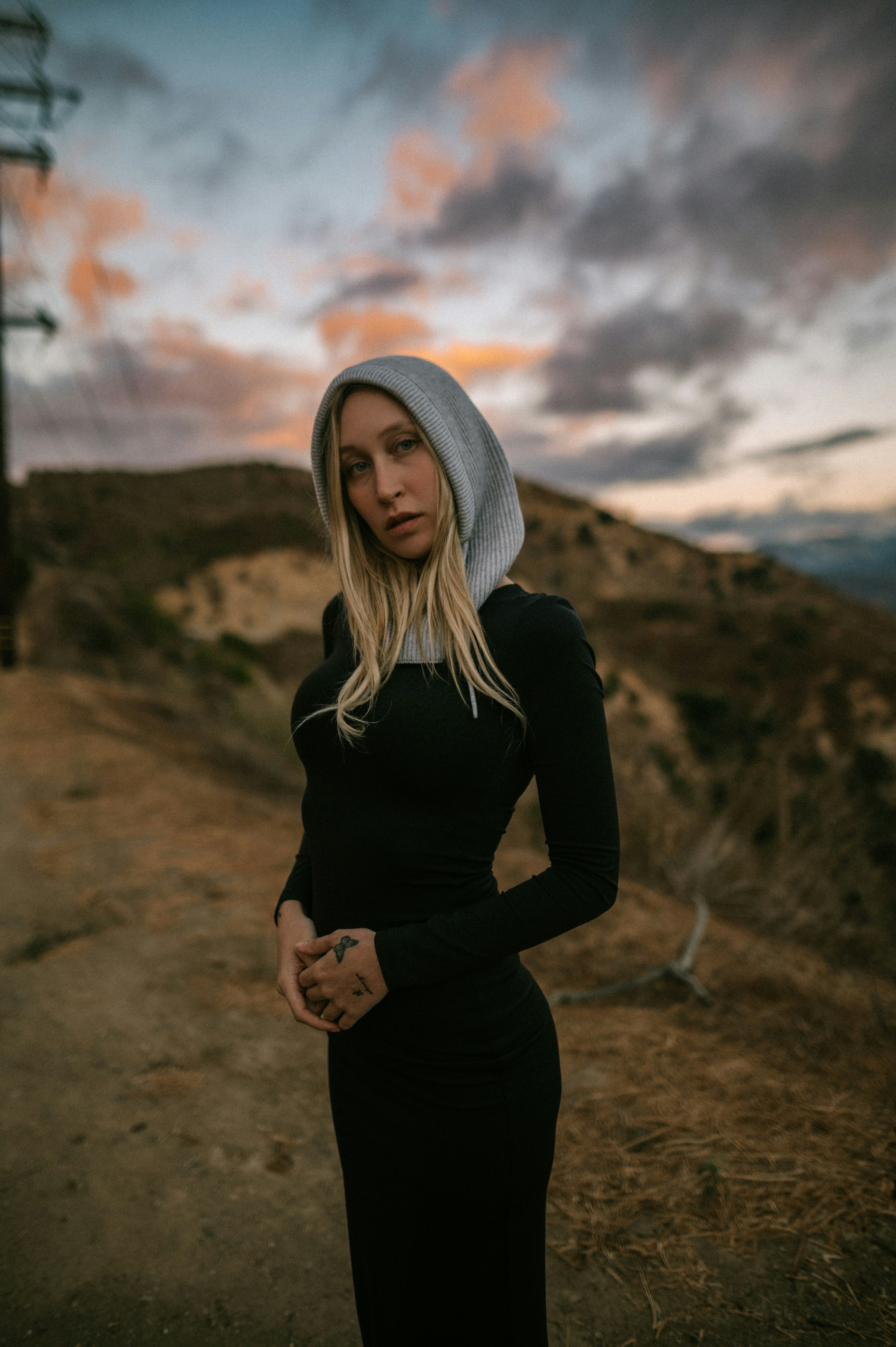 A woman in a black dress standing on a dirt road