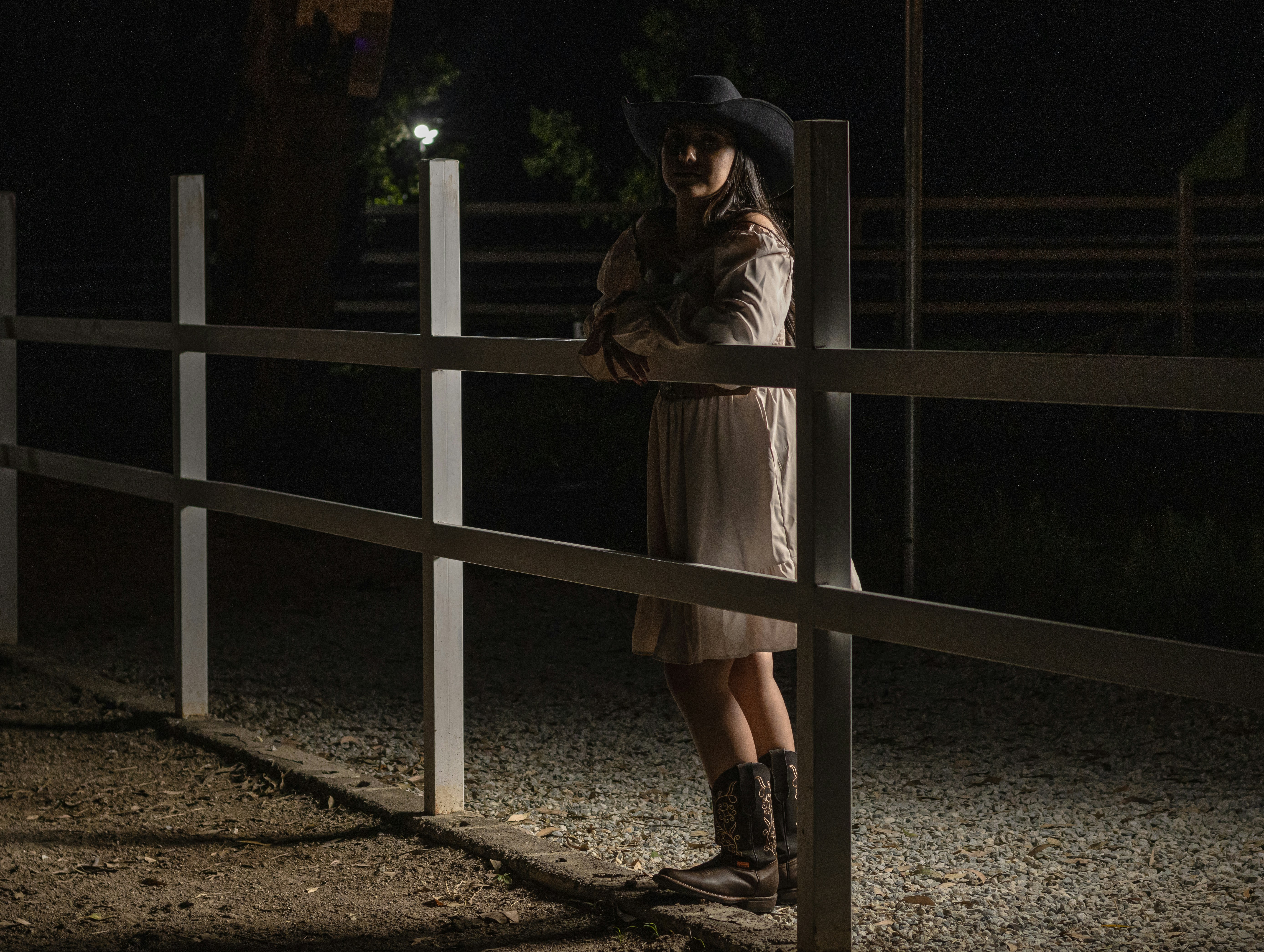 A woman in a kimono standing next to a traditional fence at night in Gion