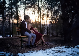 A man and woman sitting on a bench in the snow