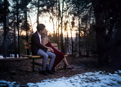 A man and woman sitting on a bench in the snow