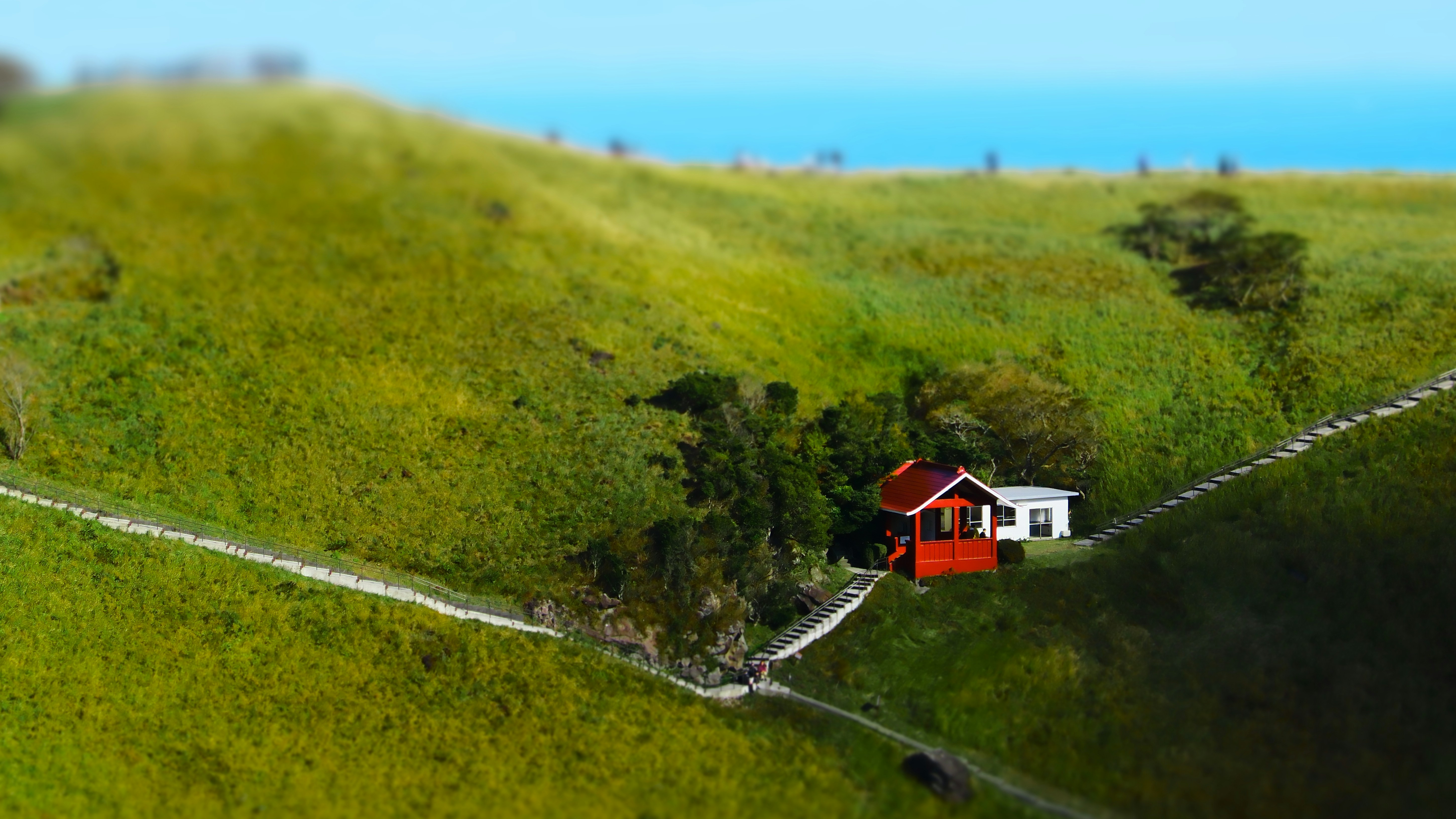 A red house sitting on top of a lush green hillside