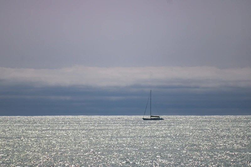 Fotografie: o velieră singuratică pe ocean, sub cerul albastru