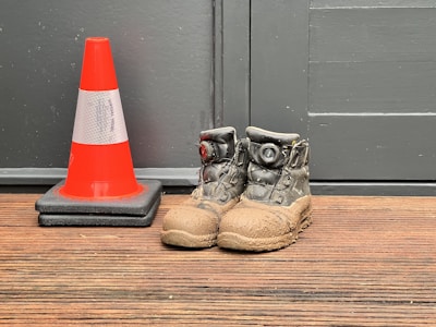 A pair of shoes sitting next to a traffic cone