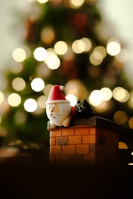A small santa clause figurine sitting on top of a brick chimney