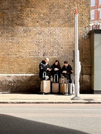 A group of people sitting on a bench next to luggage