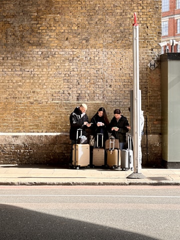 A group of people sitting on a bench next to luggage
