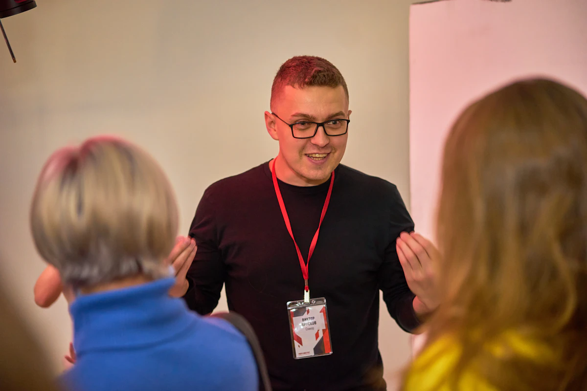A man gesturing with both hands and laughing mid-sentence while two colleagues listen