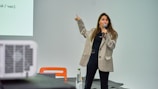 A woman standing in front of a projector screen giving a presentation