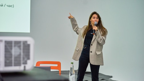 A woman standing in front of a projector screen giving a presentation