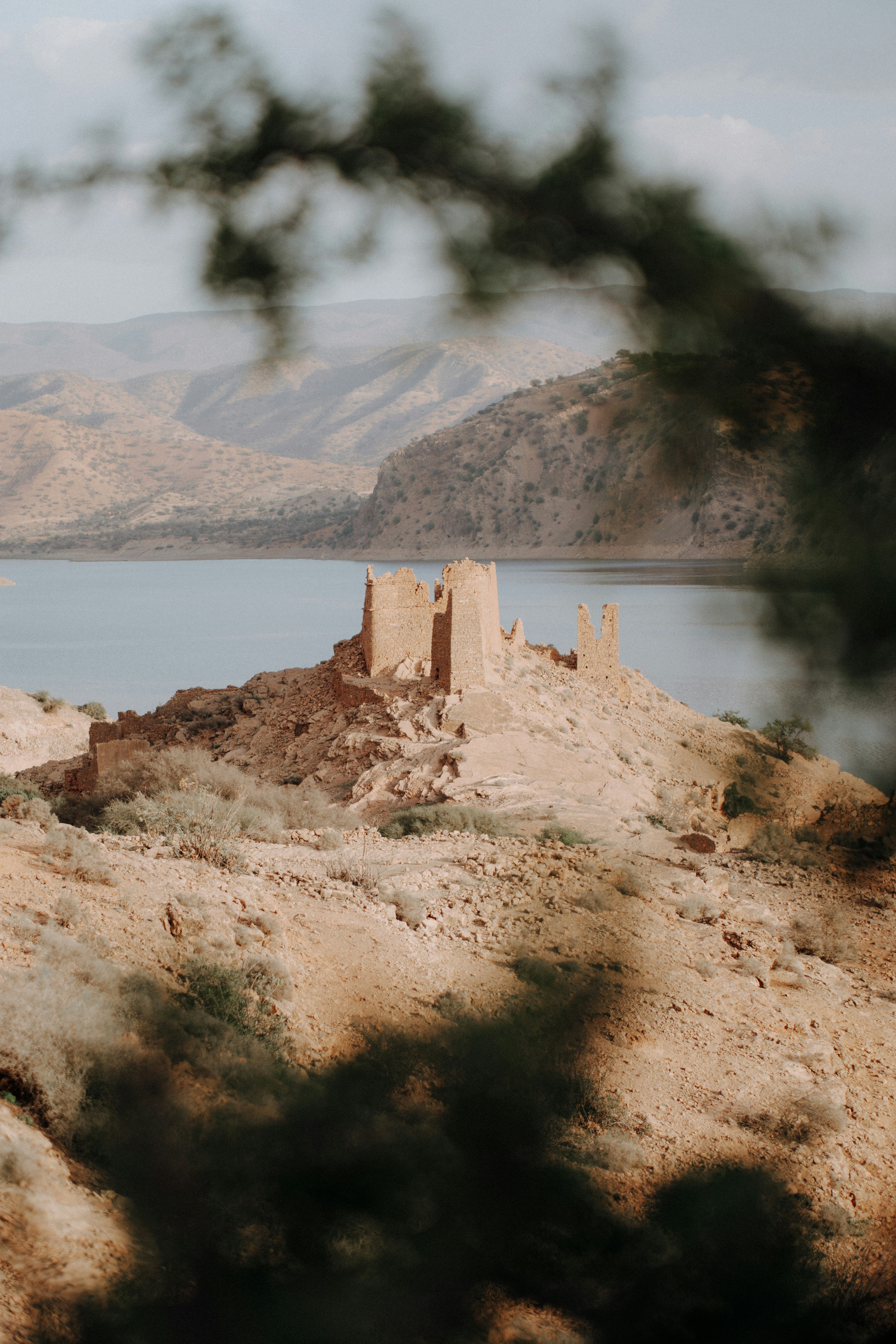 A castle sits on a hill overlooking a body of water photo – Free ...