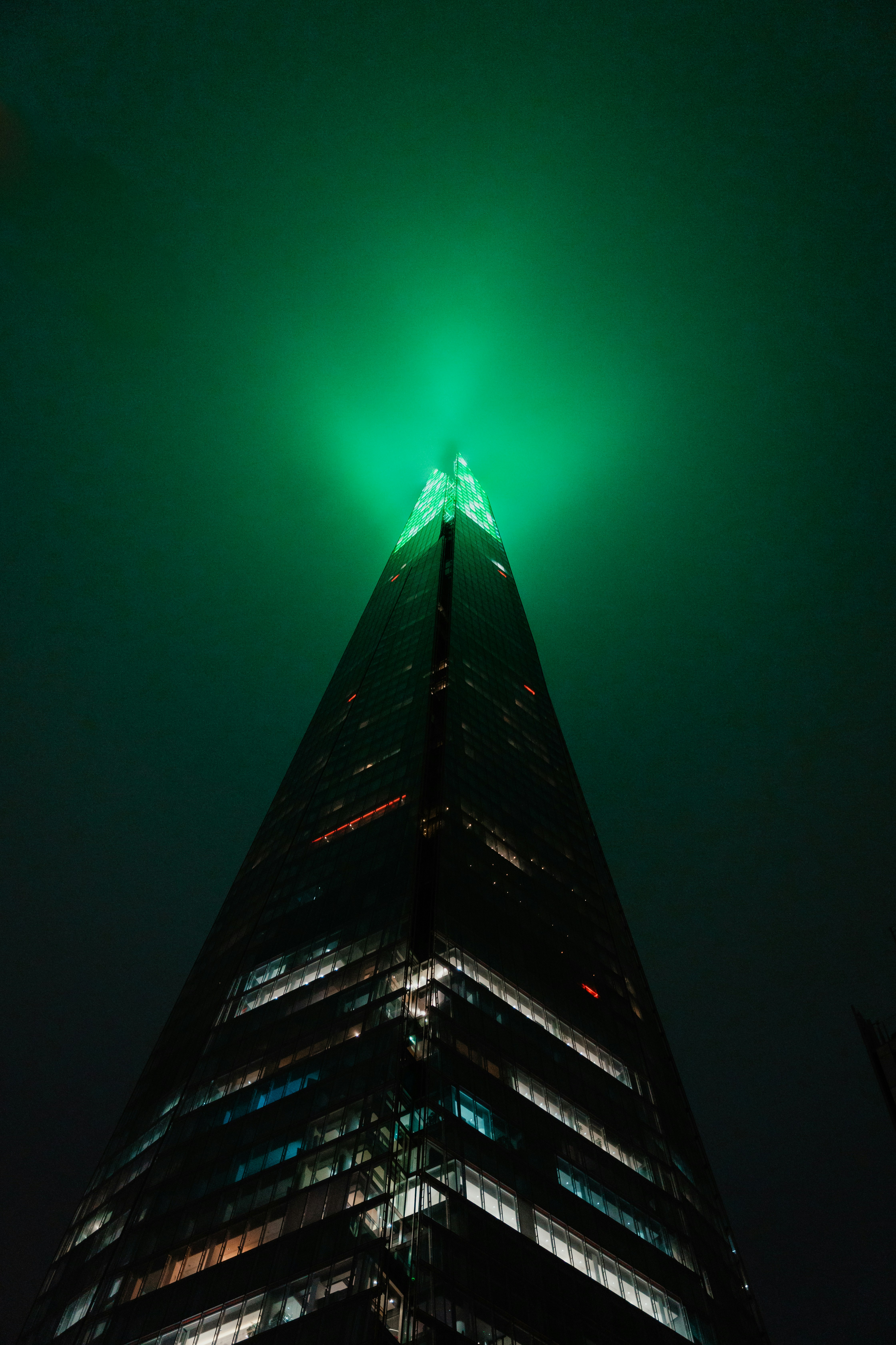A very tall building with a green light on top of it