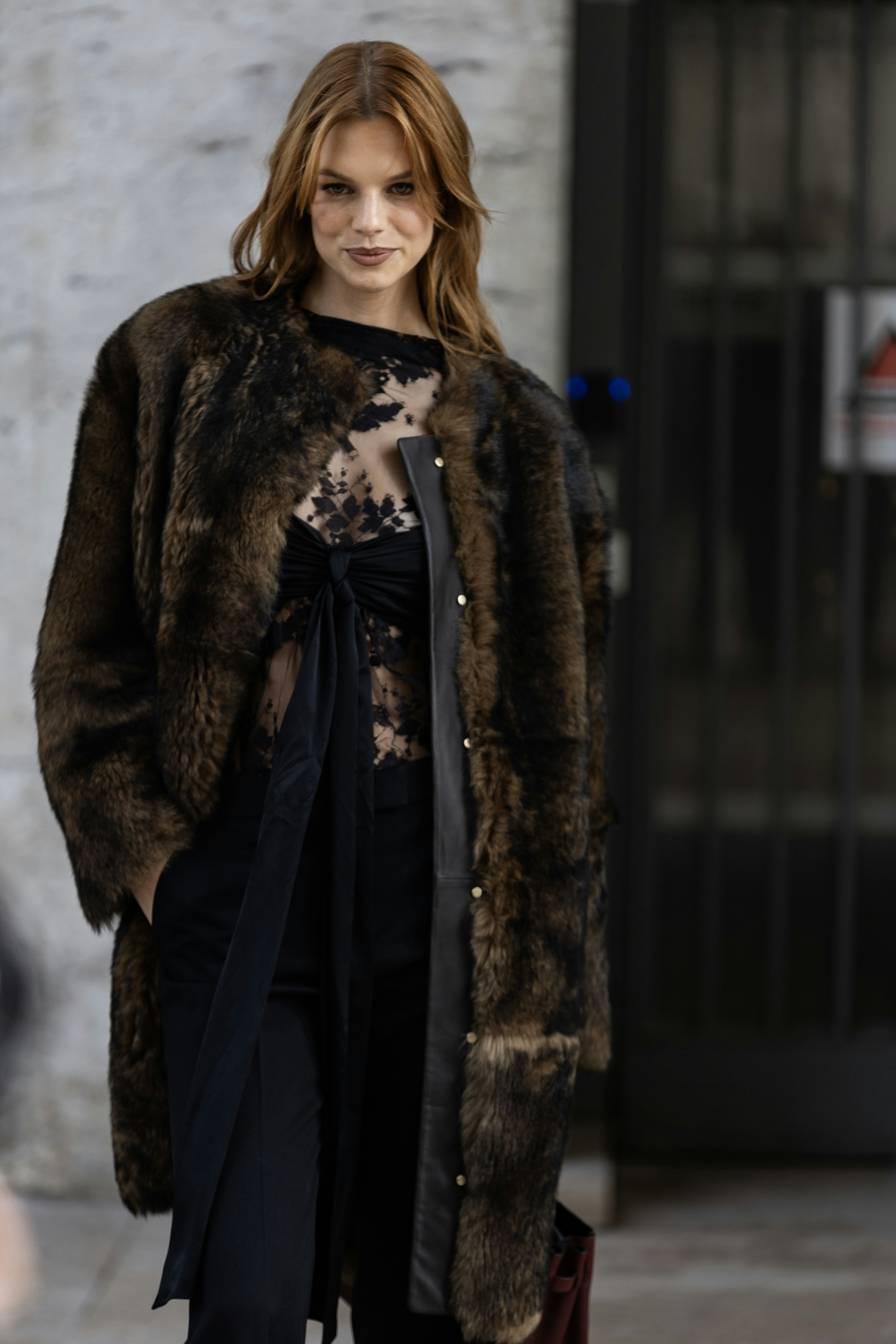 A woman is walking down the street in a fur coat