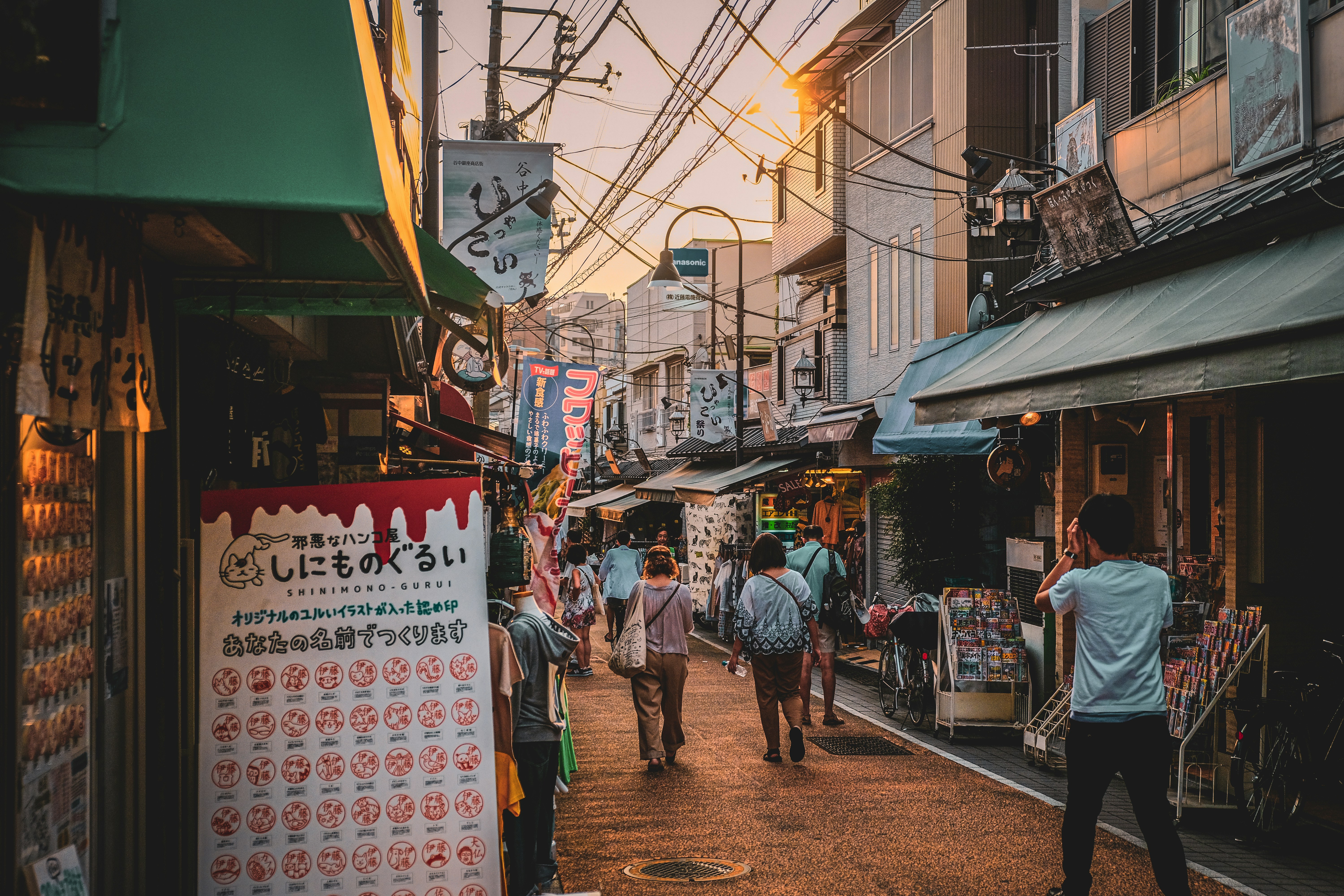 A group of people walking down a street next to tall buildings