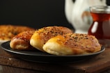 A black plate topped with pancakes next to a cup of tea