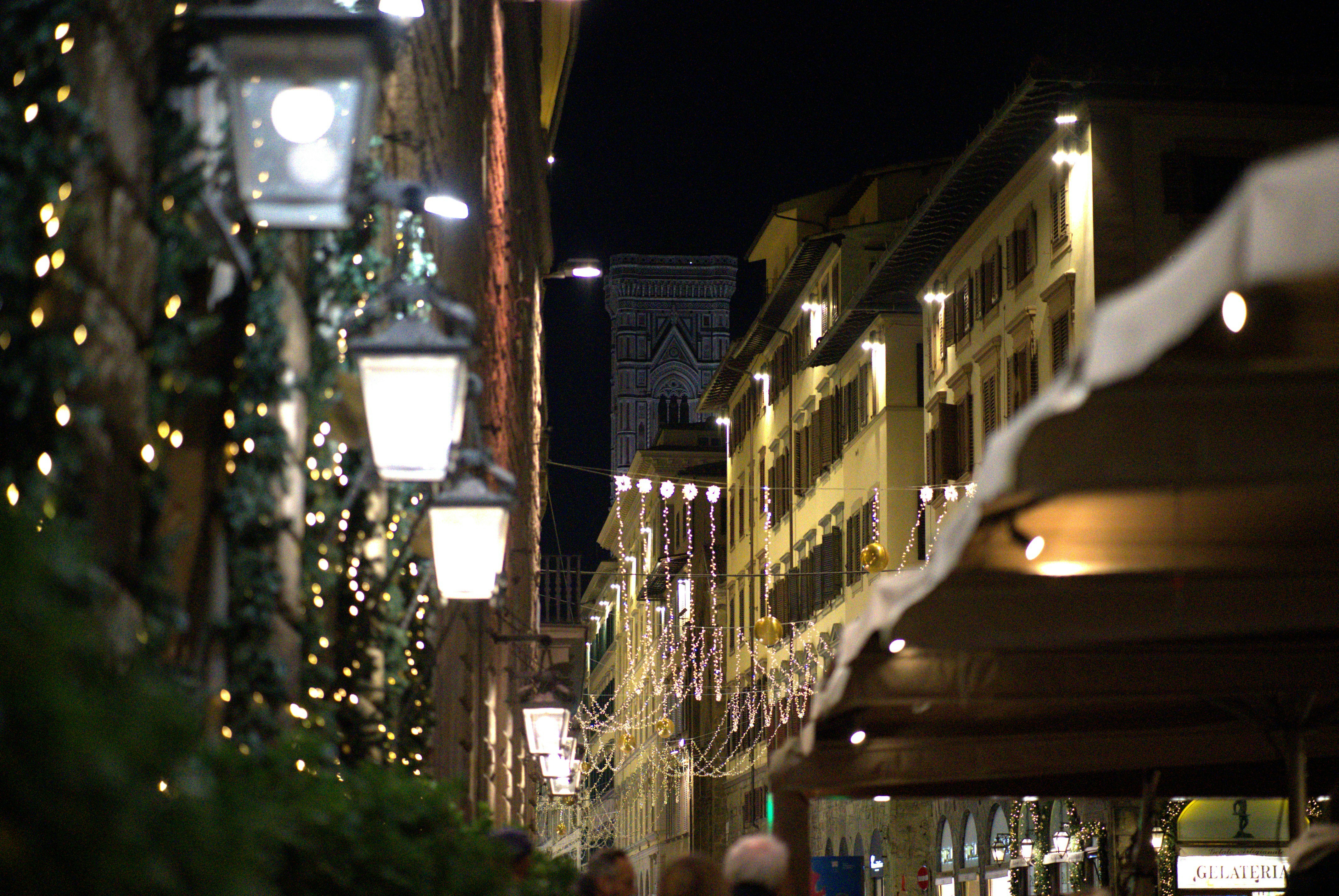 A city street at night with people walking down it