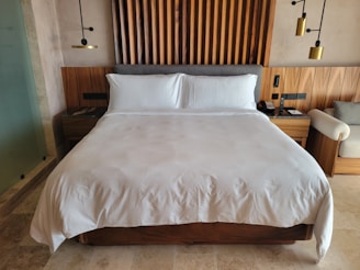 A bed with white sheets and pillows in a bedroom