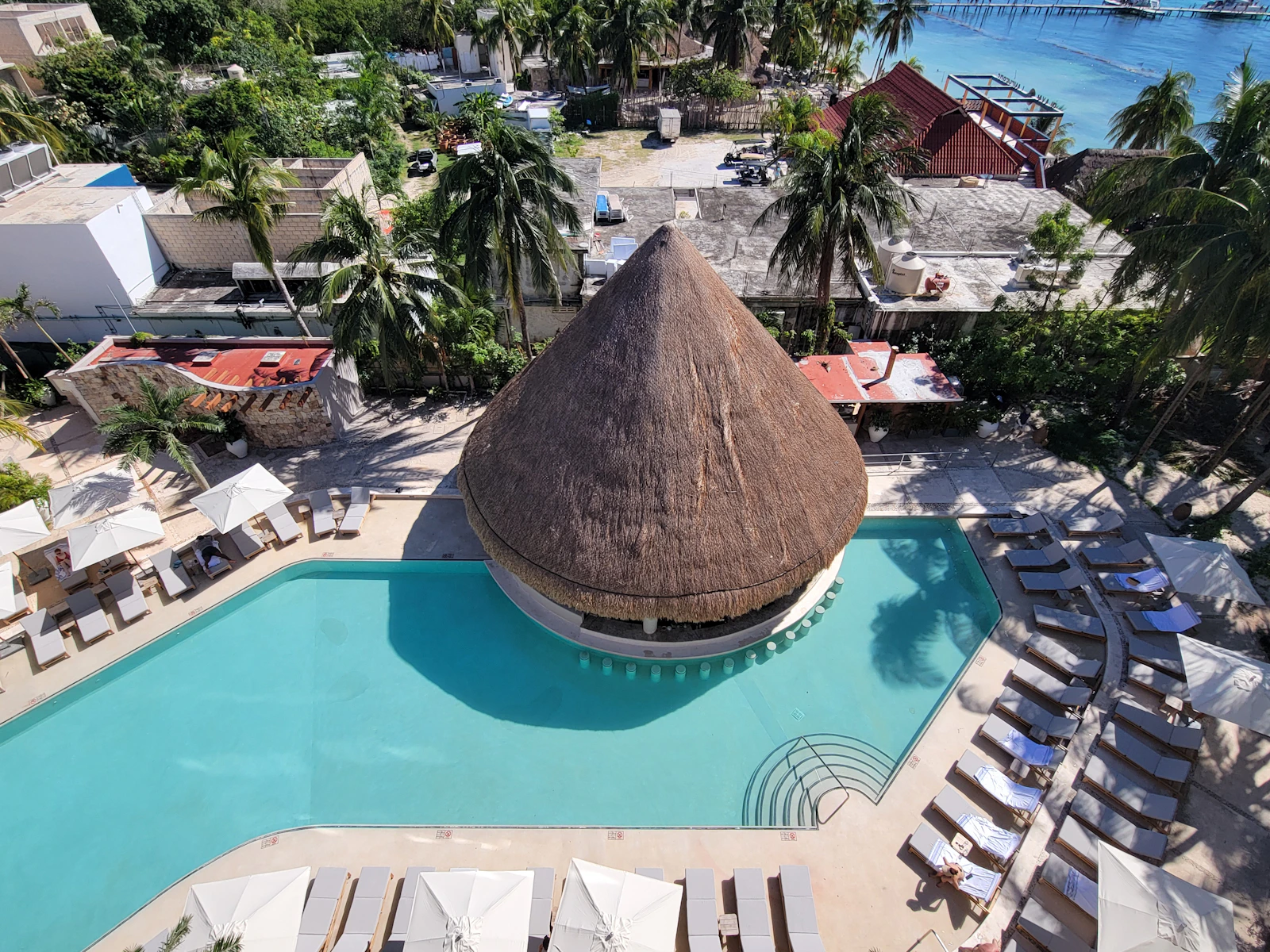An aerial view of a beachfront all-inclusive resort pool, loungers and swim-up bar in Isla Mujeres