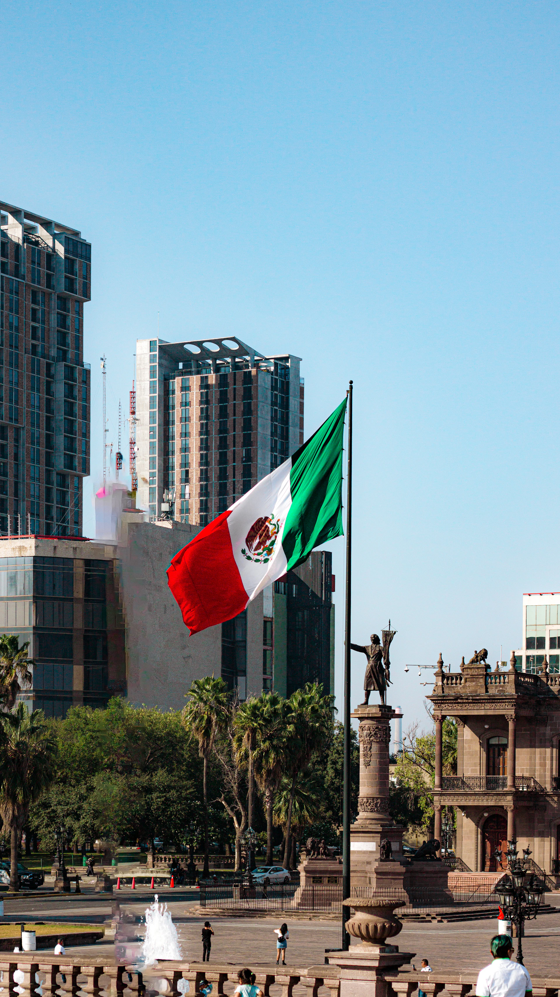 A mexican flag flying in the wind in a city
