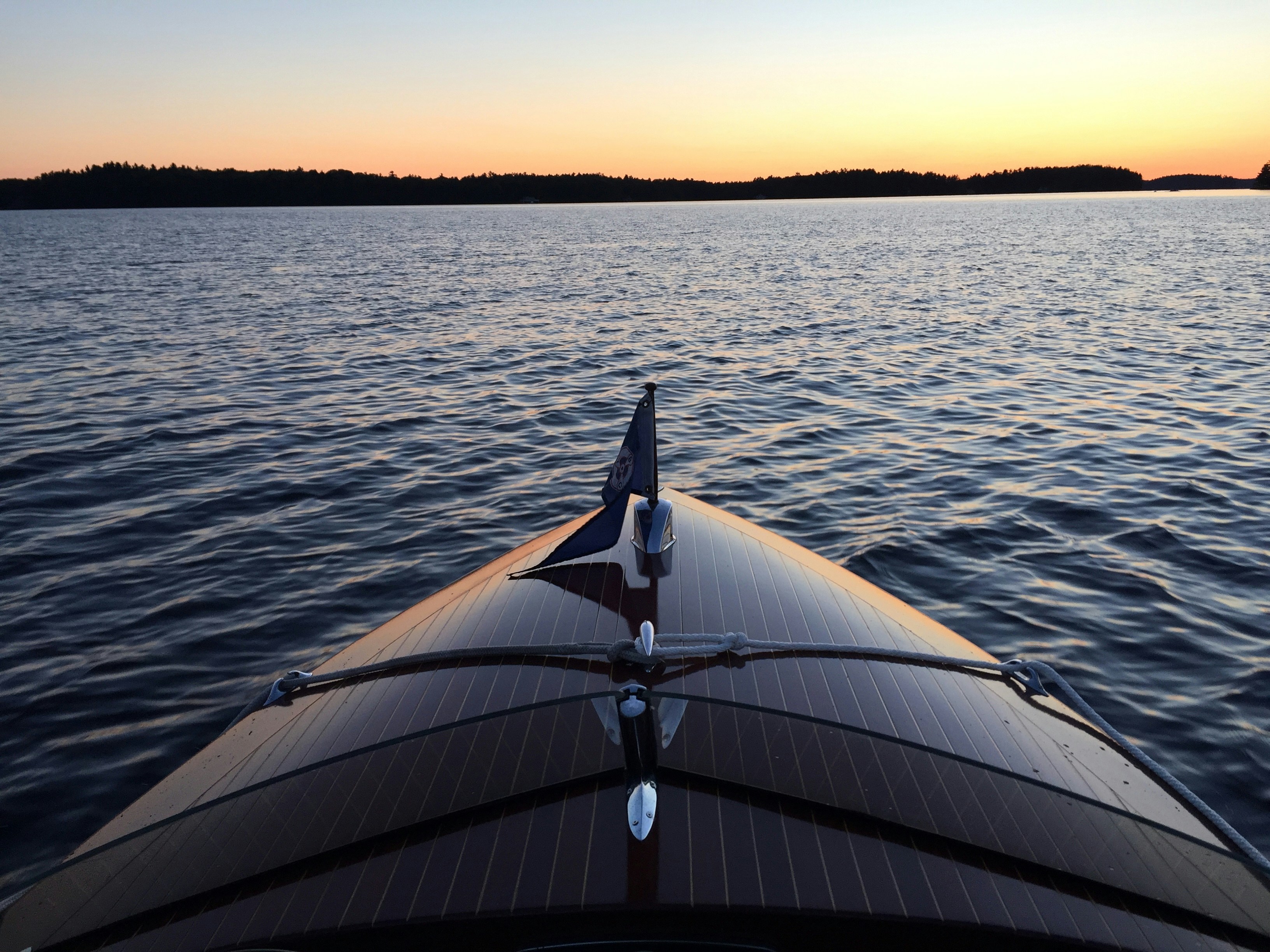 Wooden sailing boat at sunset on calm water