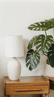 A white vase sitting on top of a wooden table next to a lamp