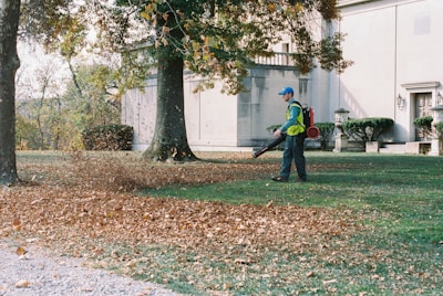 A man with a leaf blower in a yard