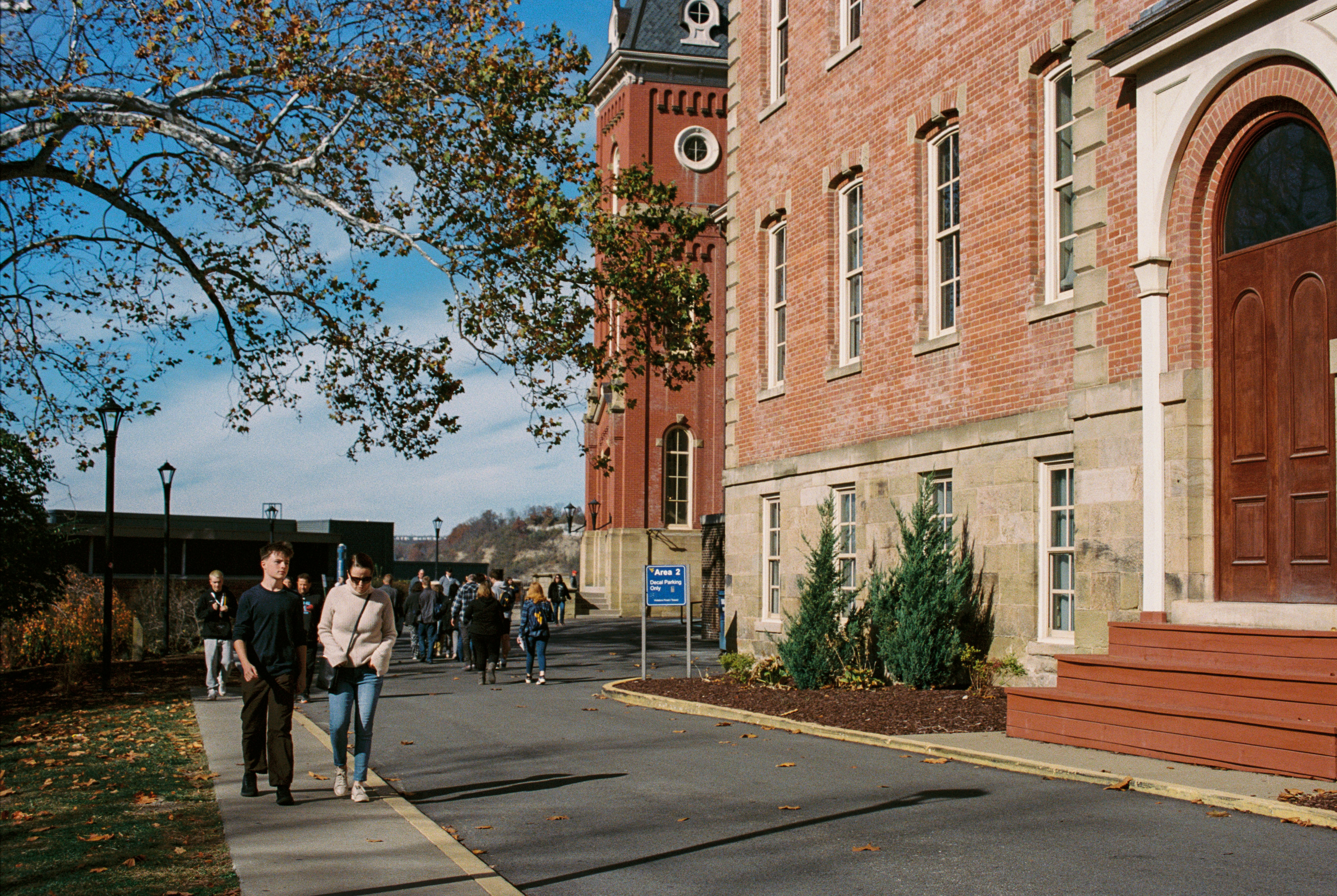 A group of people walking down a street next to a tall building