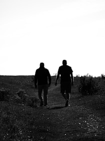 A couple of men walking down a dirt road