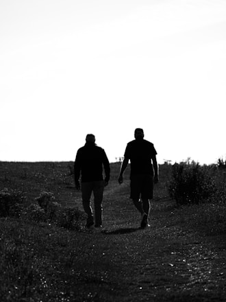 A couple of men walking down a dirt road
