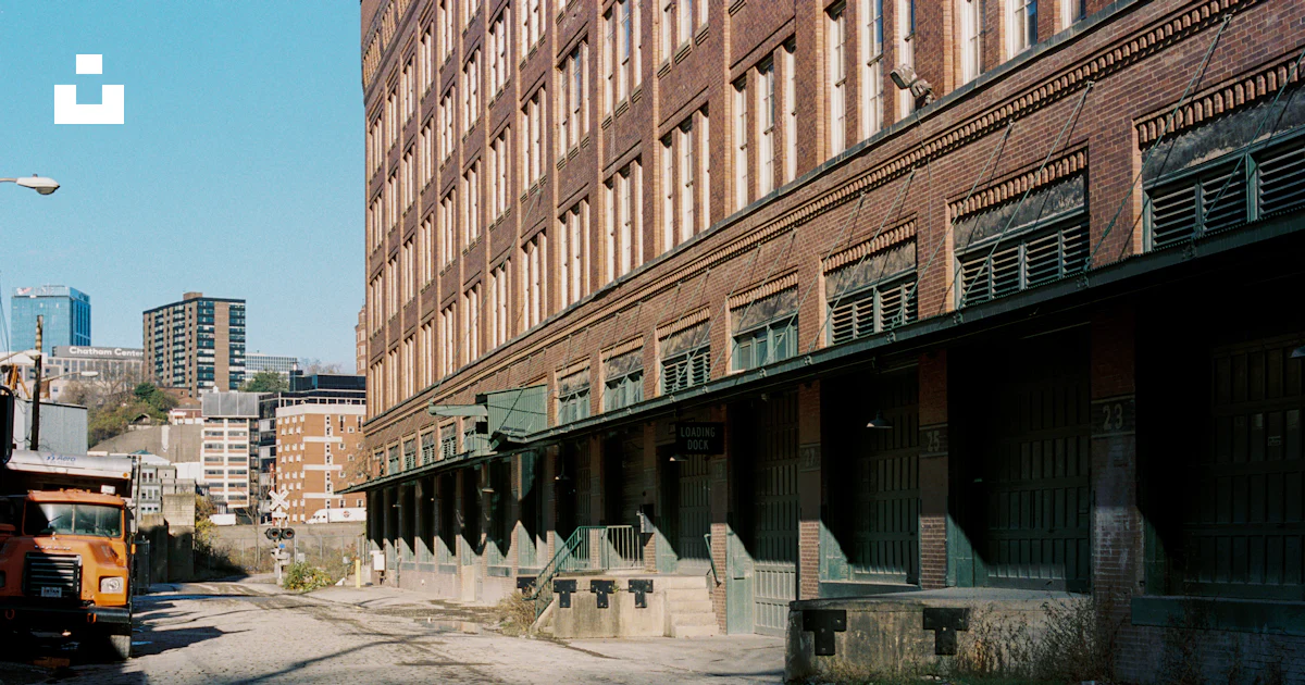 A large brick building next to a very tall building photo – Free ...