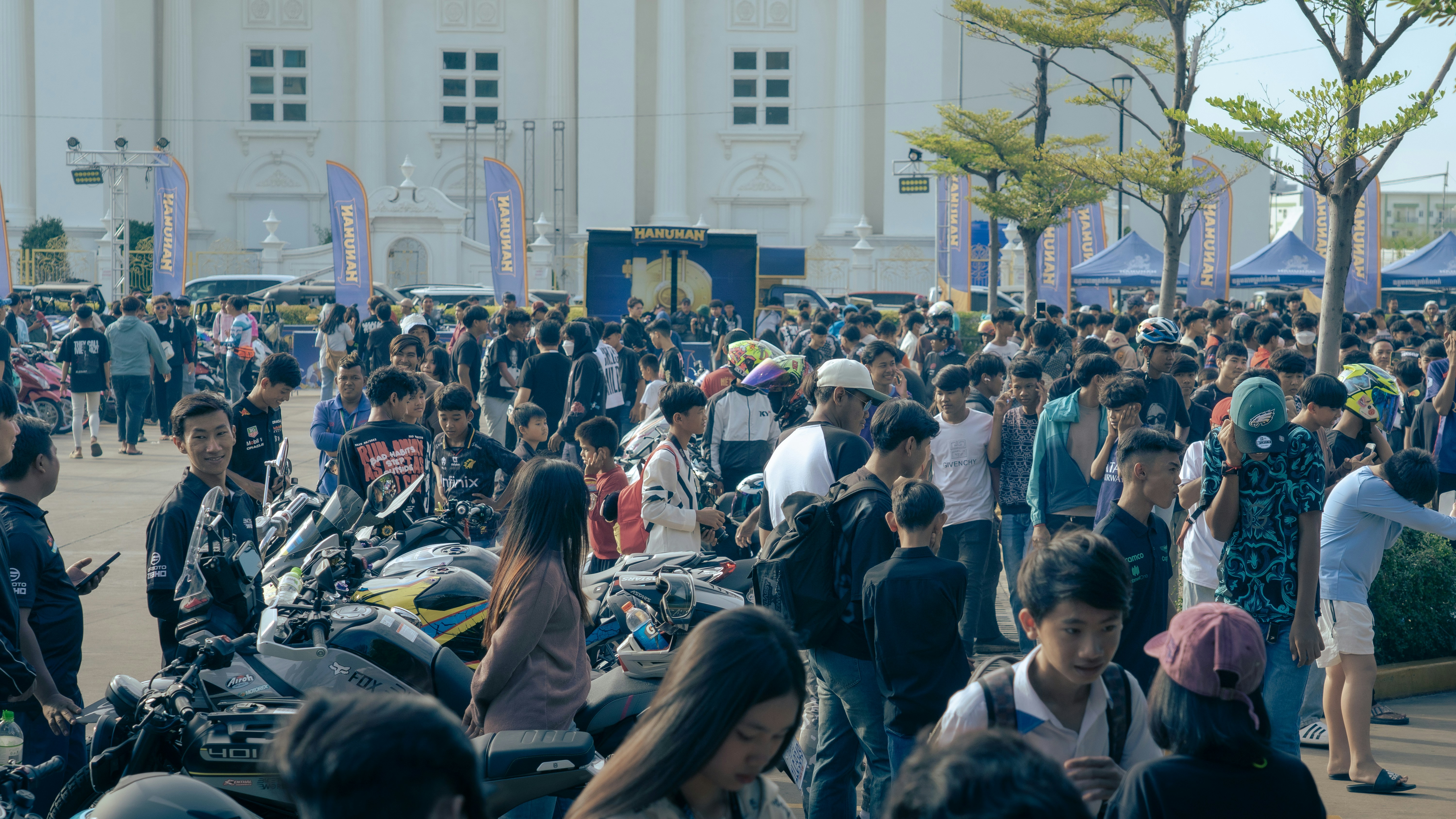 A large crowd of people walking around a building photo – Free Car ...