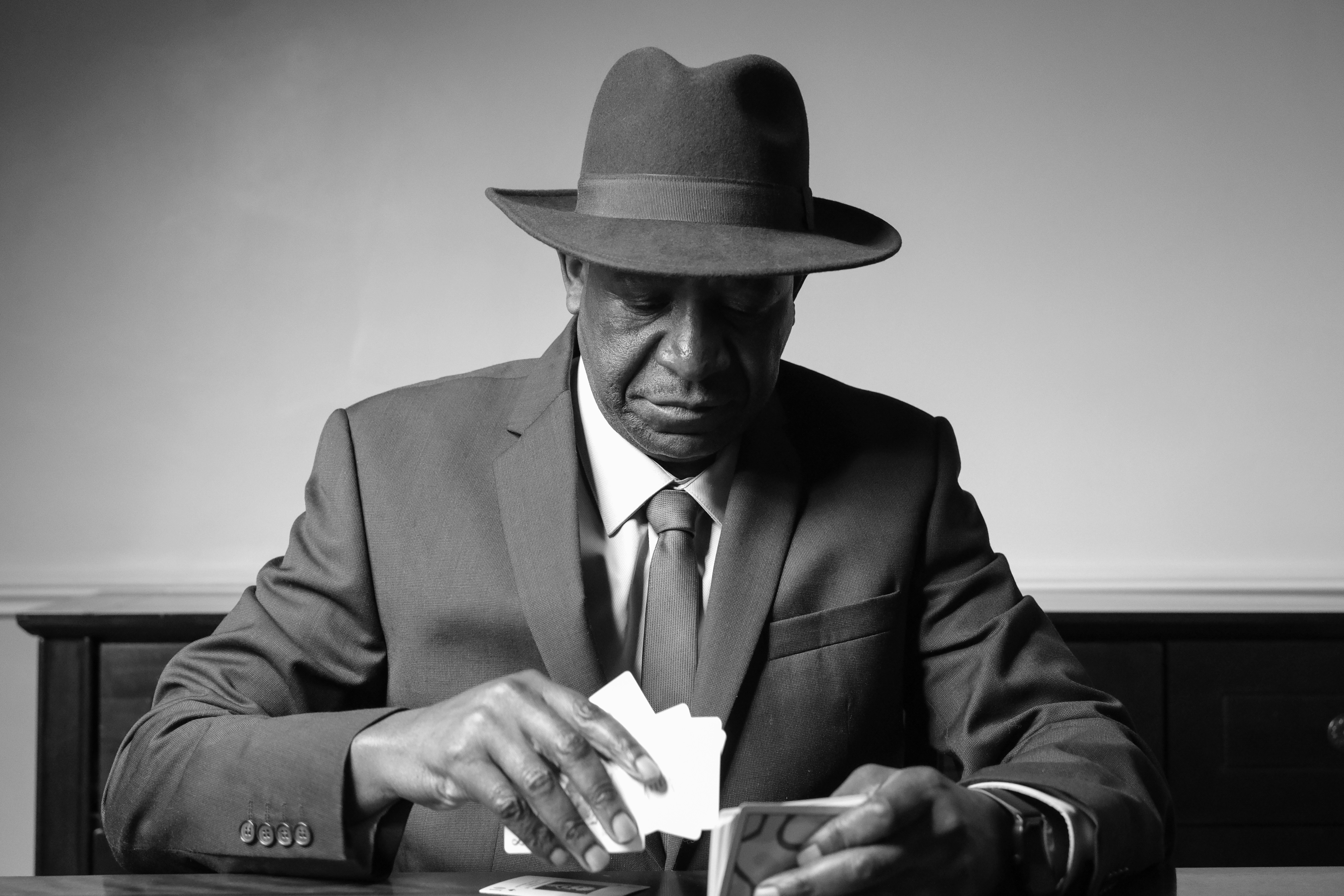 A man in a suit and hat sitting at a table