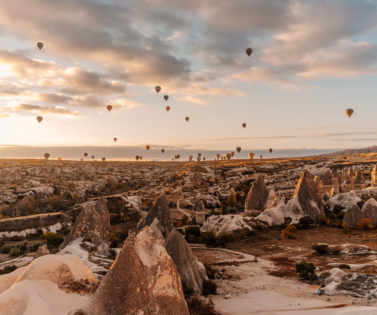 Sunrise balloons above the valleys and rock formations of Göreme