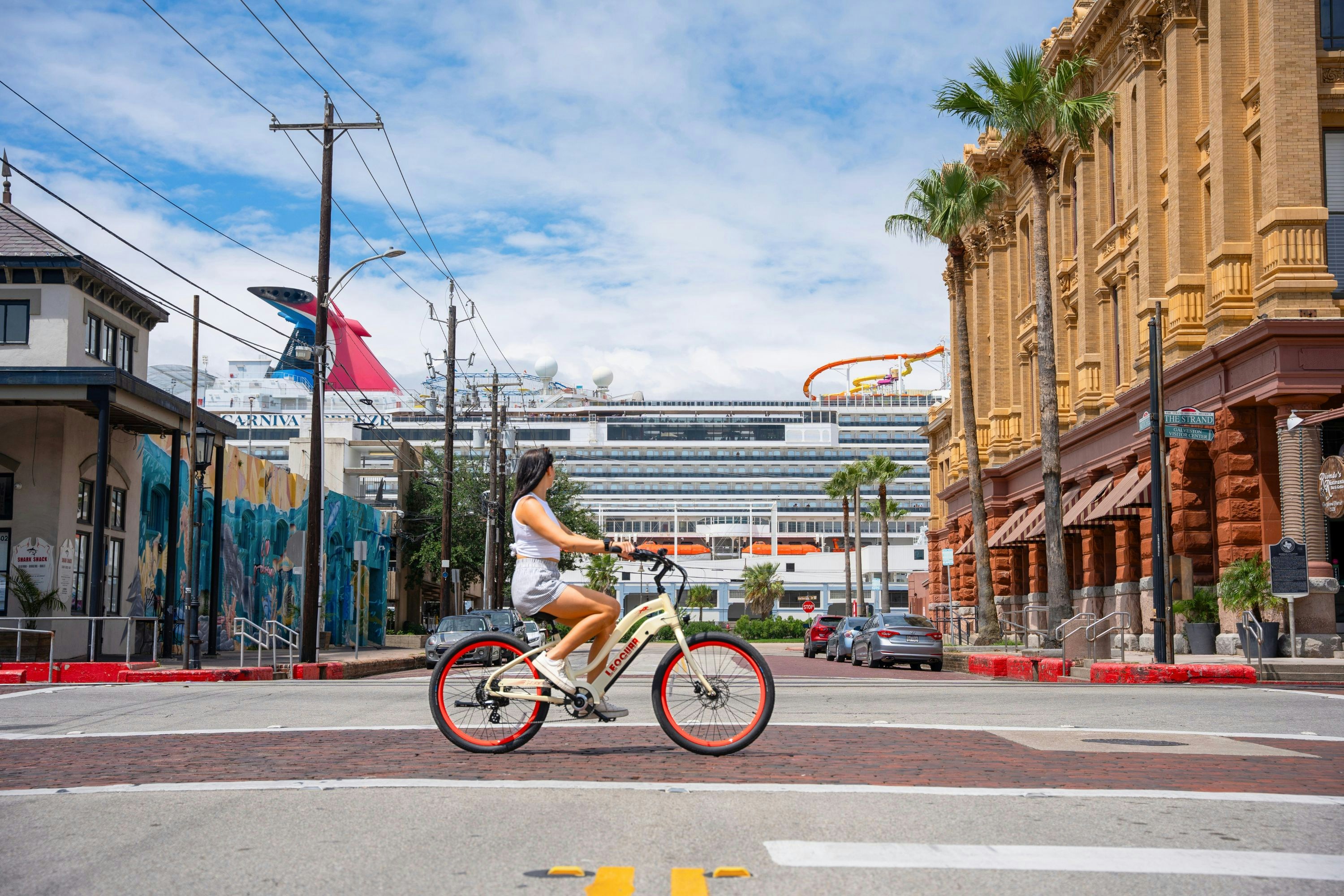 A woman riding a bike down a street next to tall buildings