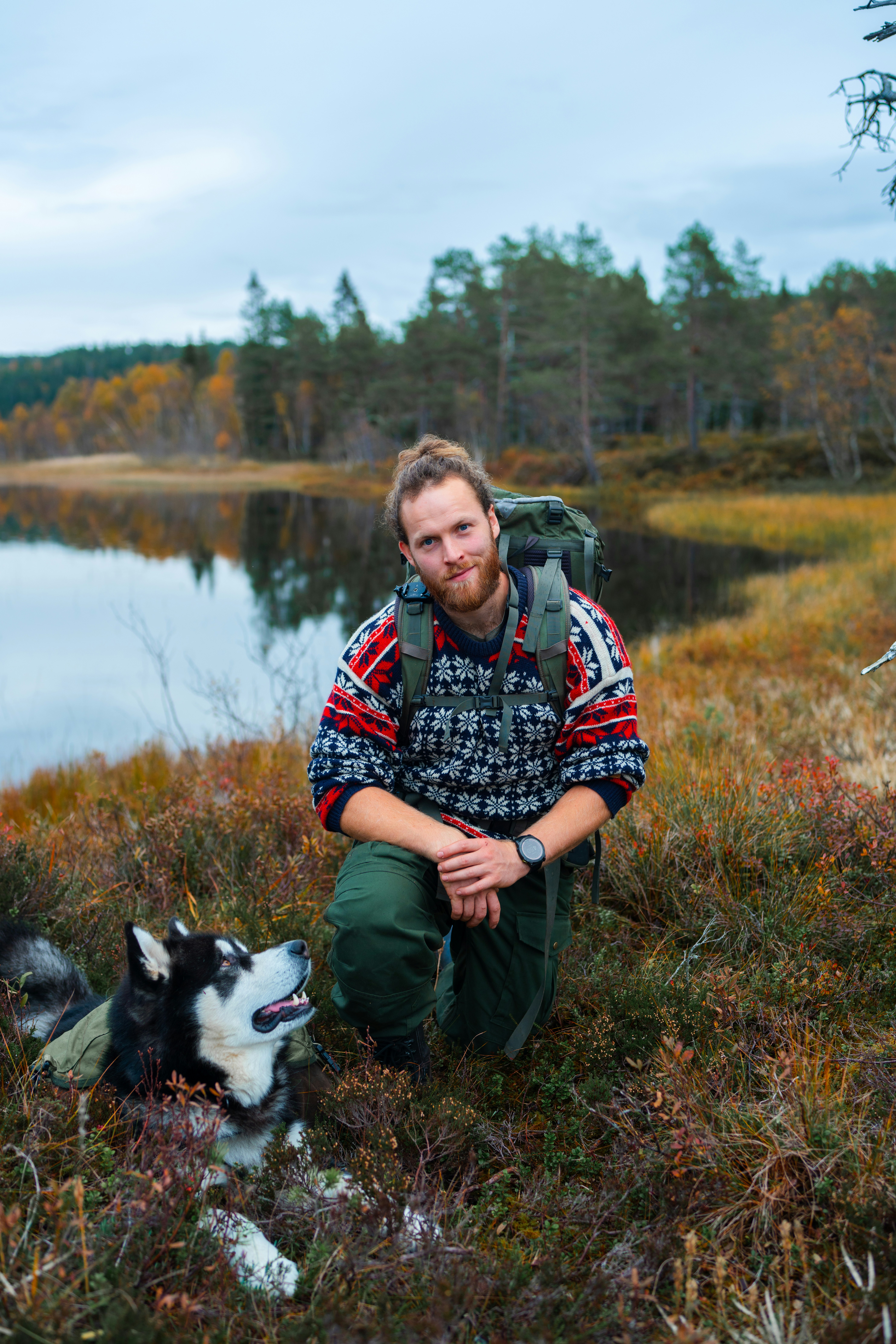 A man kneeling down next to a dog on a field