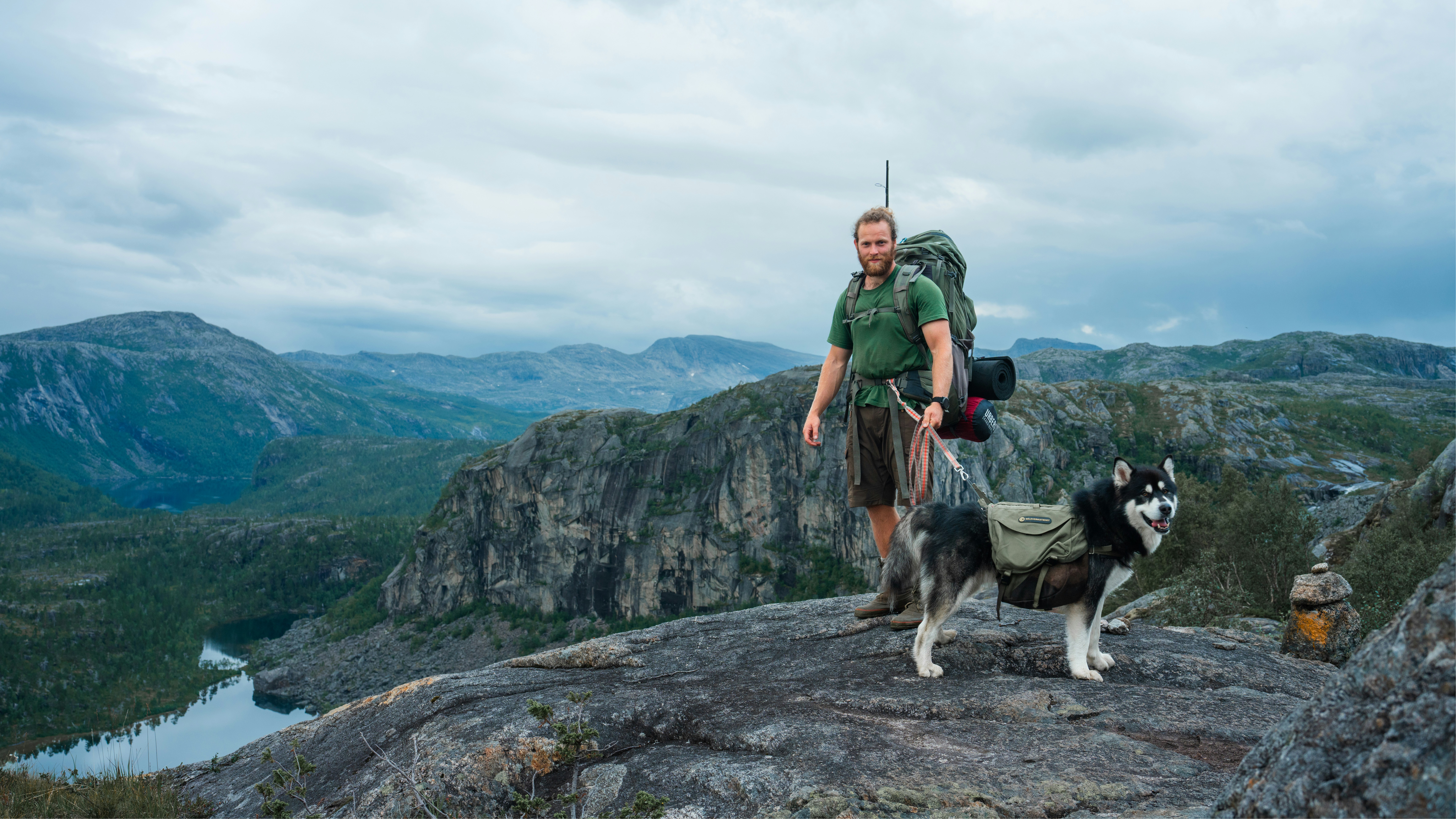A man standing on top of a mountain with a dog