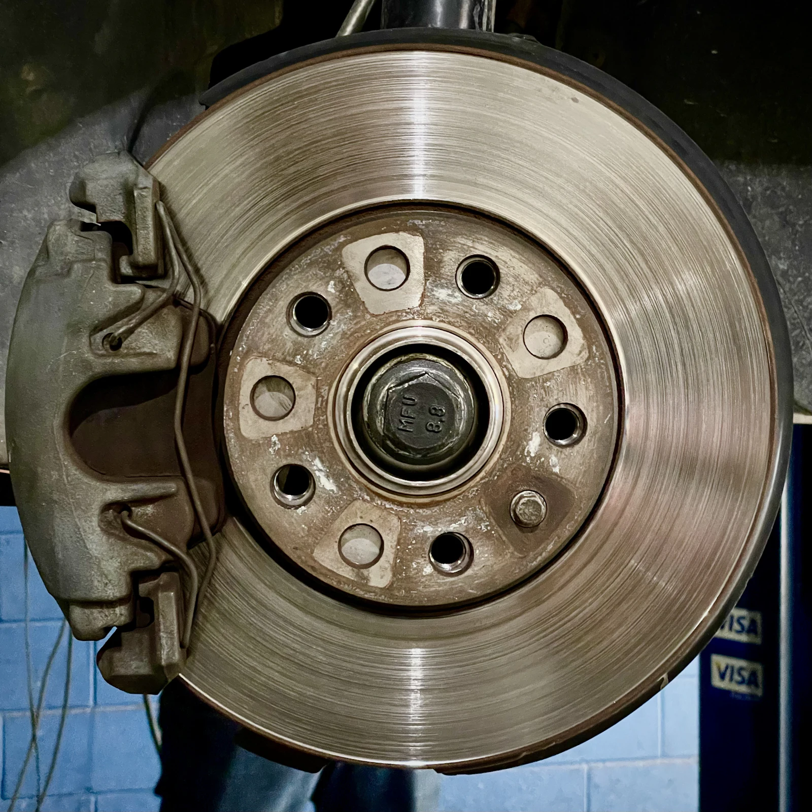 A worn brake rotor and caliper, close up