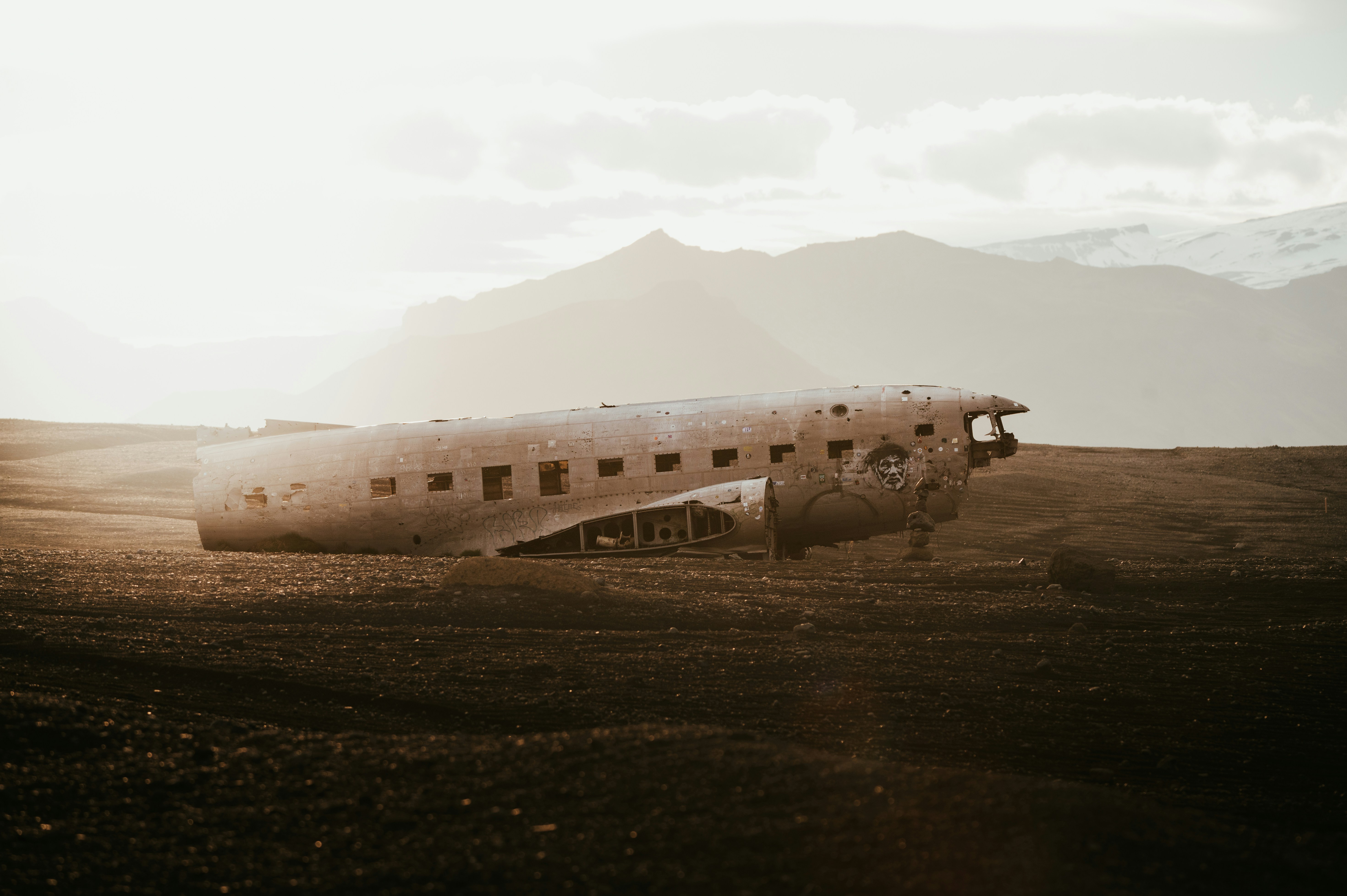 An old airplane sitting in a field with mountains in the background