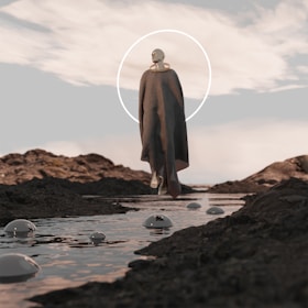A man standing on top of a rocky beach next to a body of water