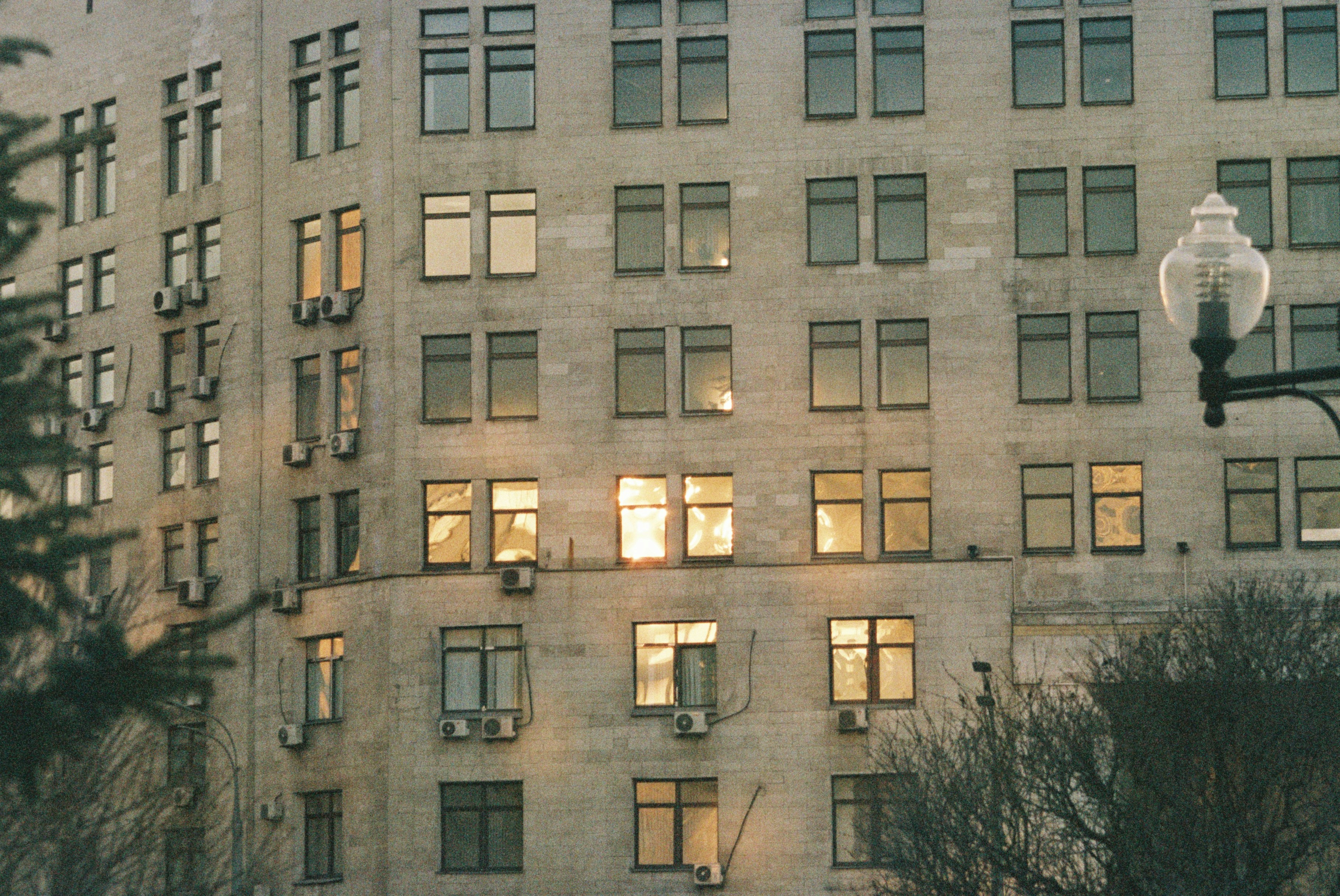 A tall building with lots of windows next to a street light