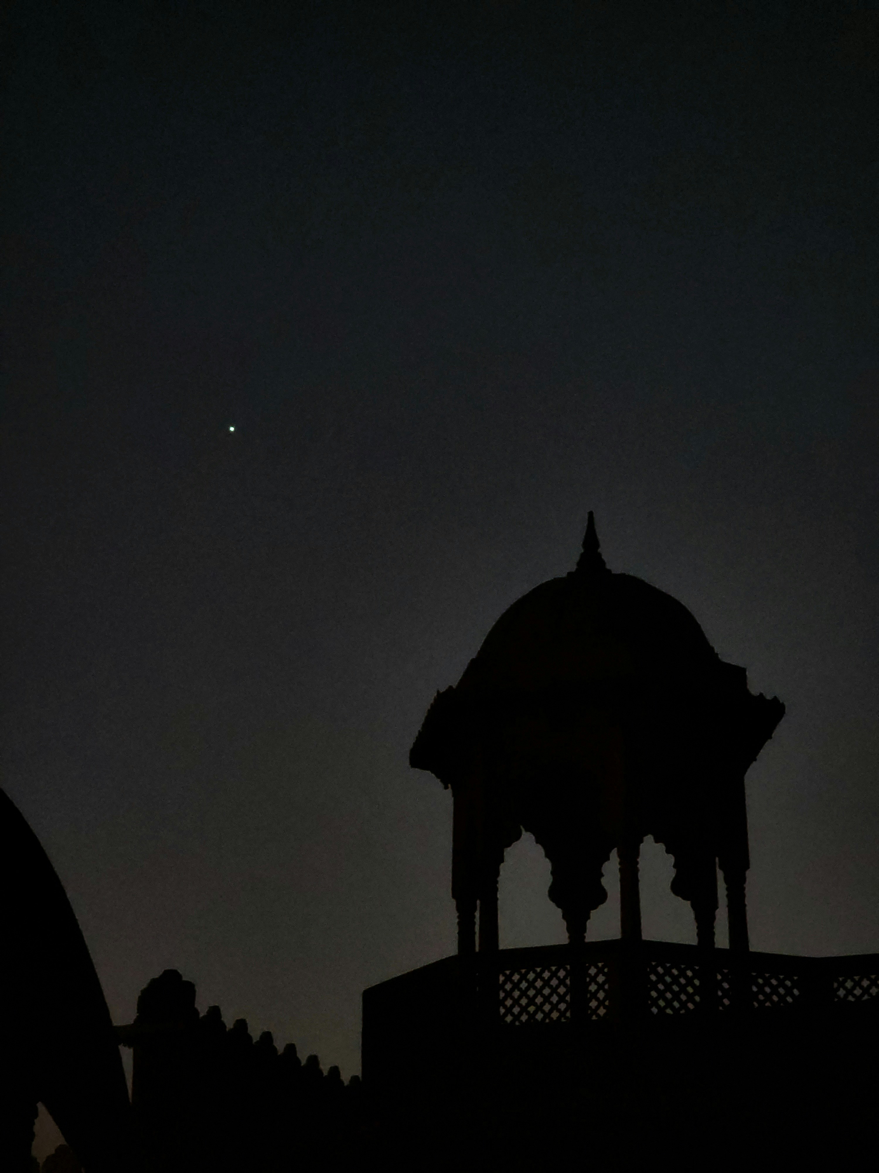 A silhouette of a gazebo and a building at night