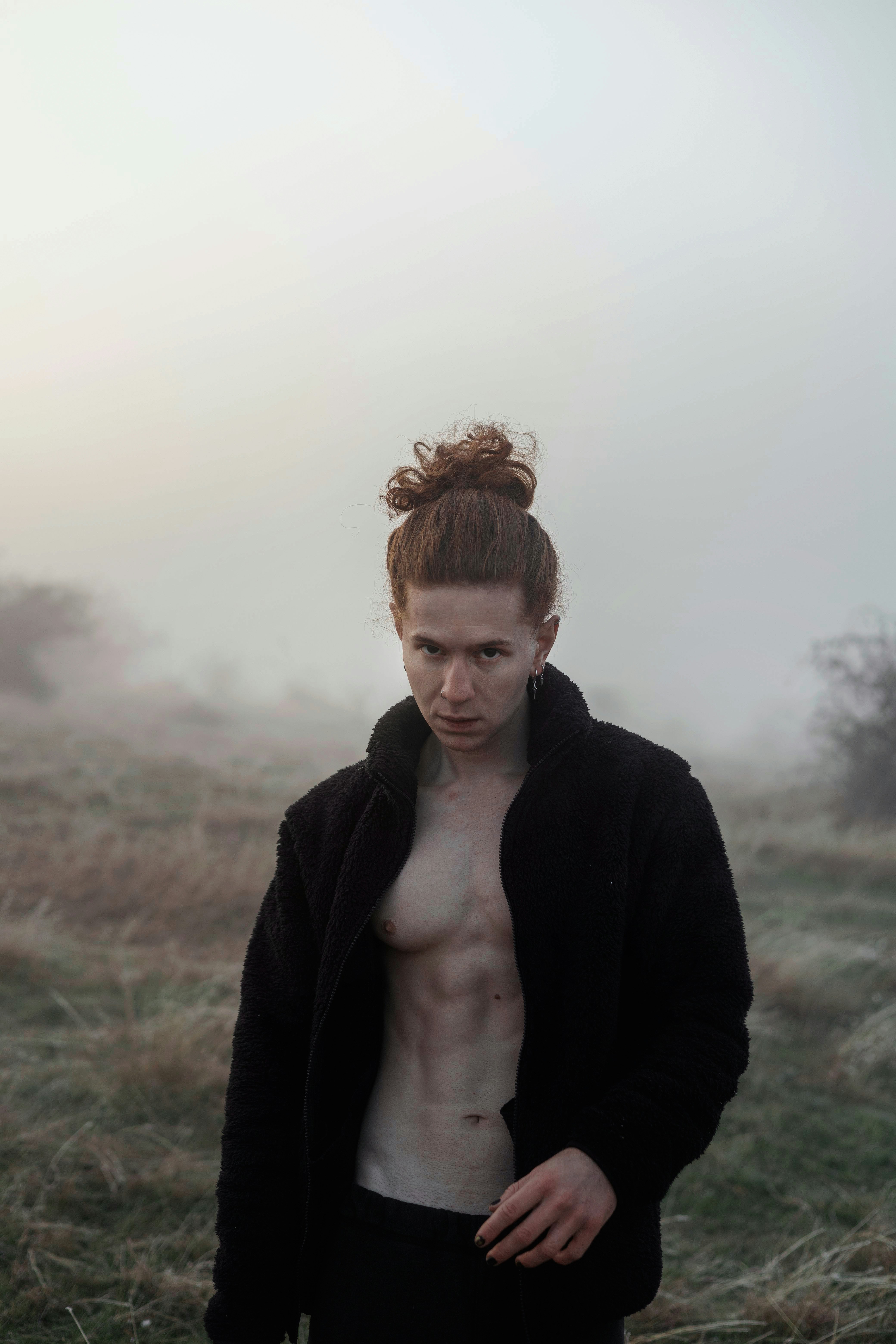 A shirtless man standing in a foggy field