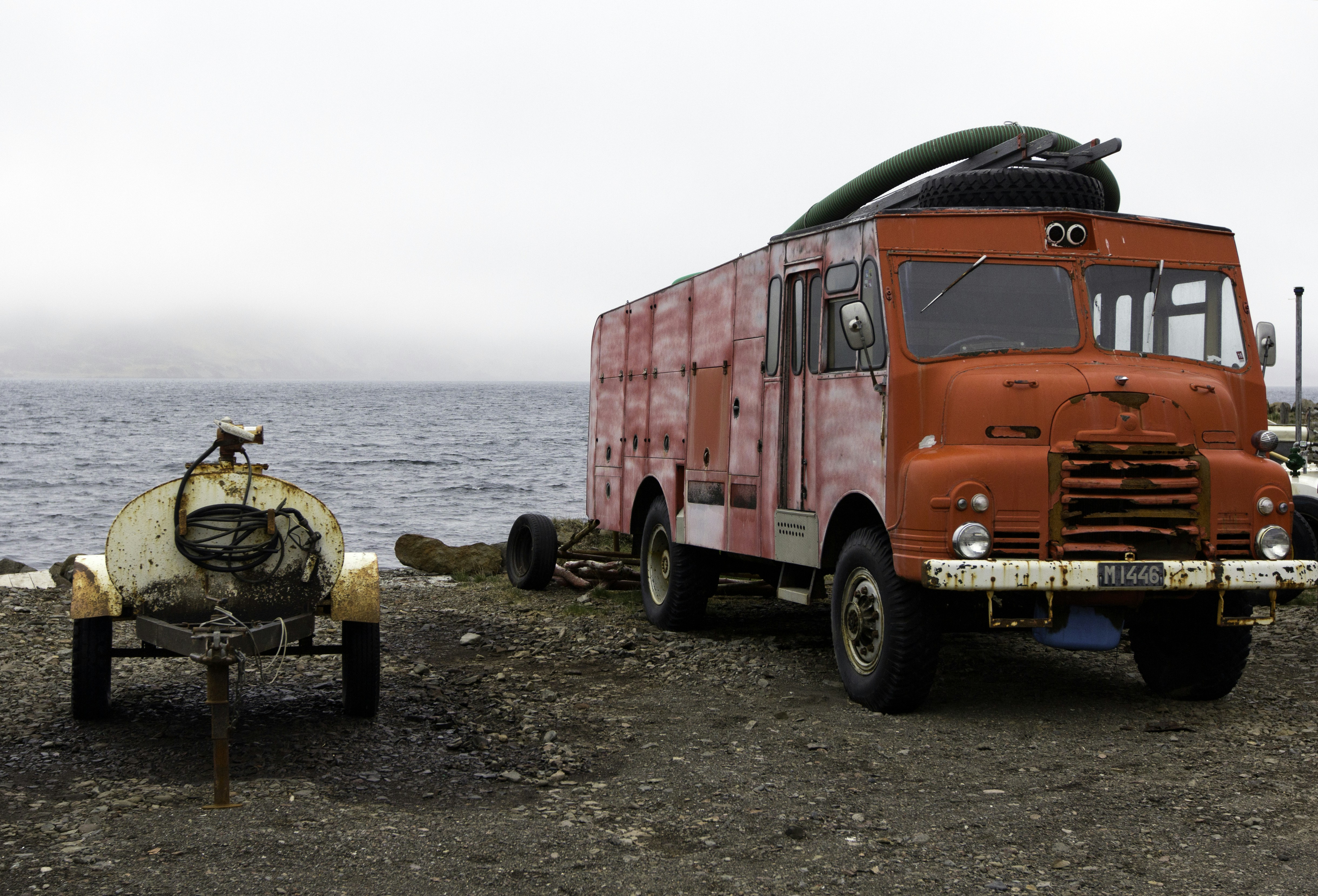A red truck parked next to a motorcycle on a beach