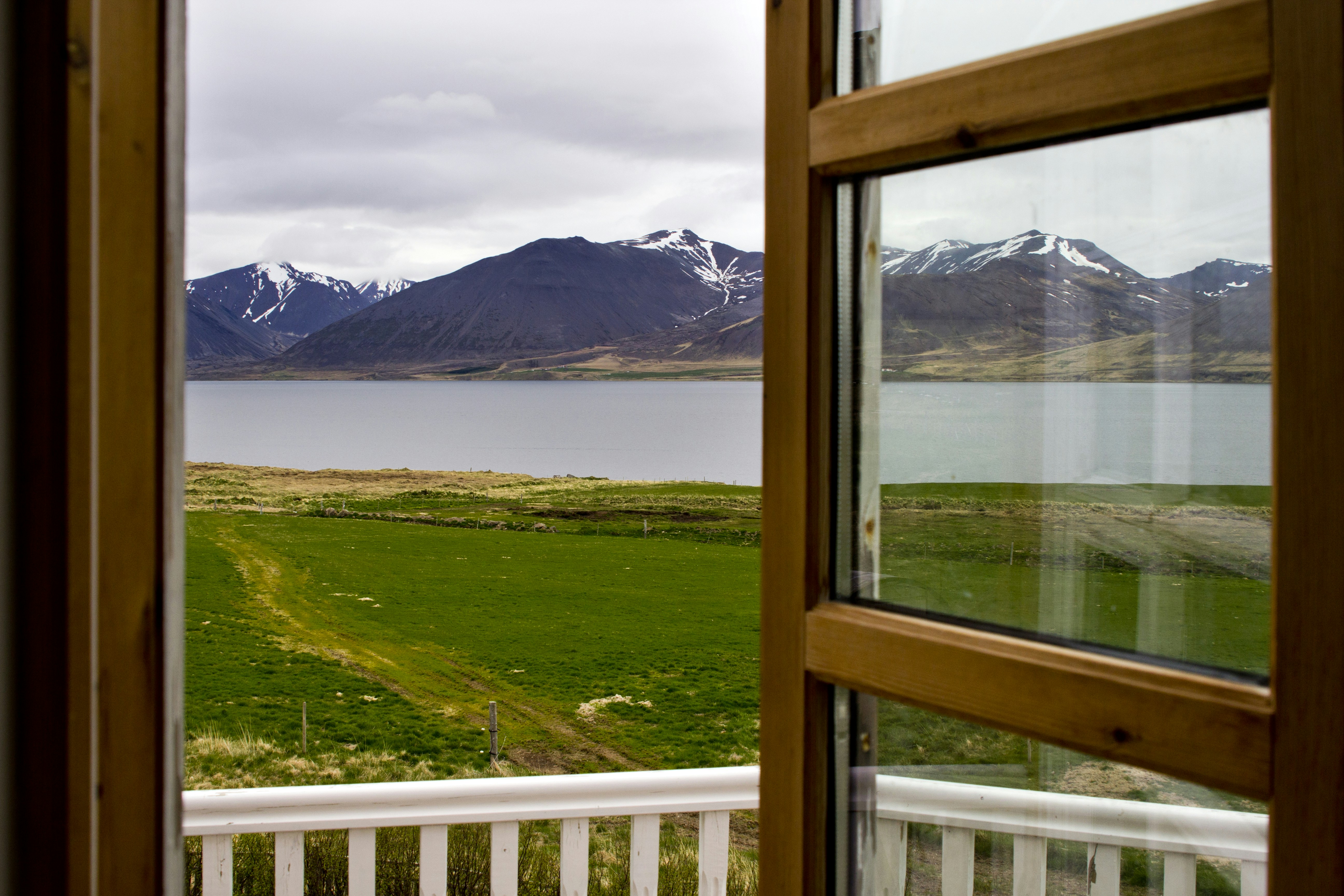 An open window with a view of a lake and mountains