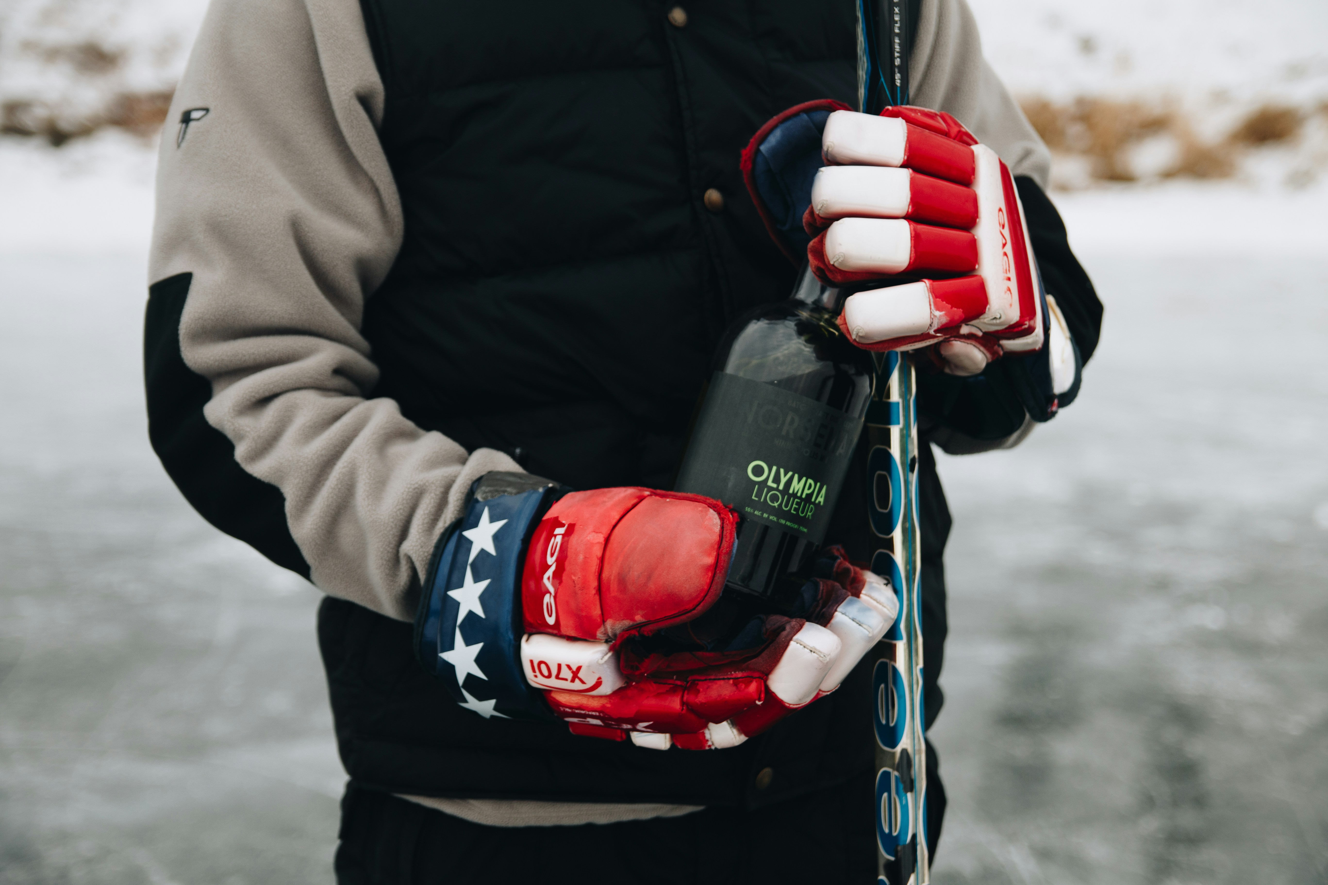 A man holding a pair of skis and a bottle of wine